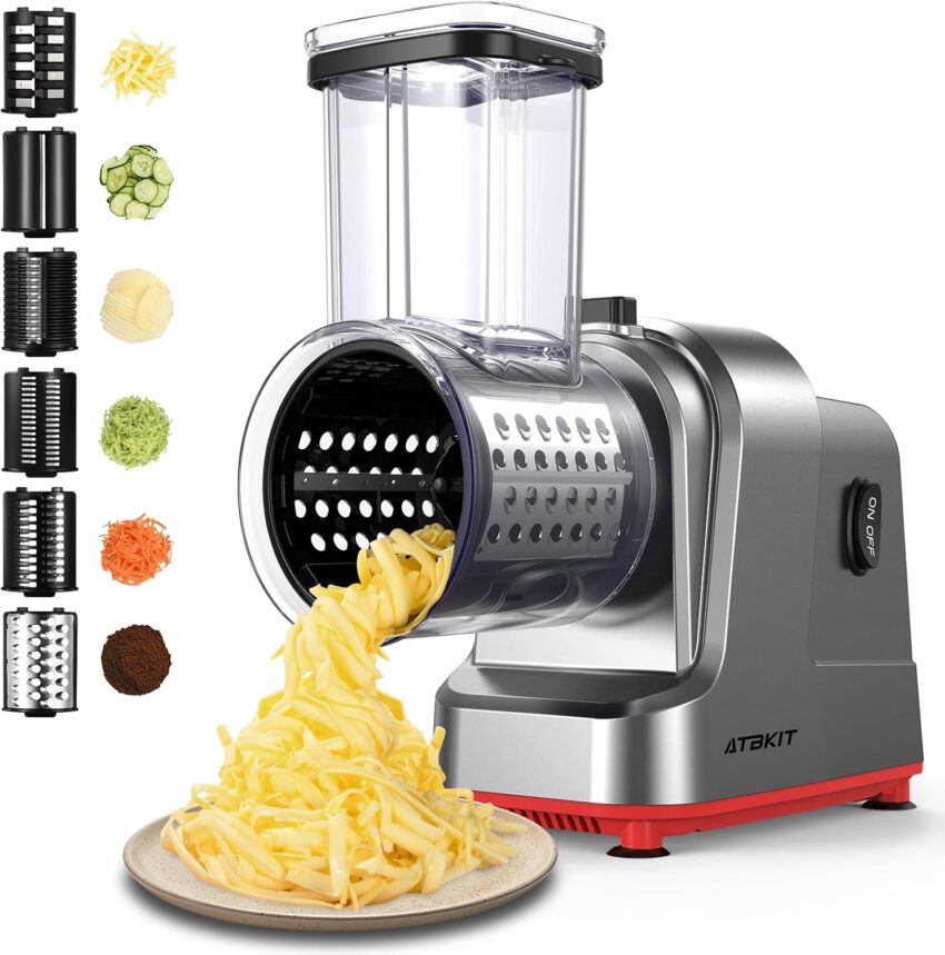 Modern electric vegetable slicer actively shreds cheese onto a plate, surrounded by interchangeable blades and fresh produce.